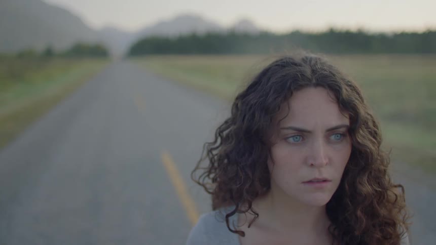 A young woman stands in the middle of a road