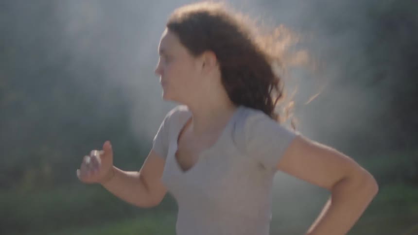 Woman runs through smoke in the forest during daylight