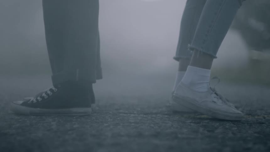 Man and woman stand back to back on a foggy road