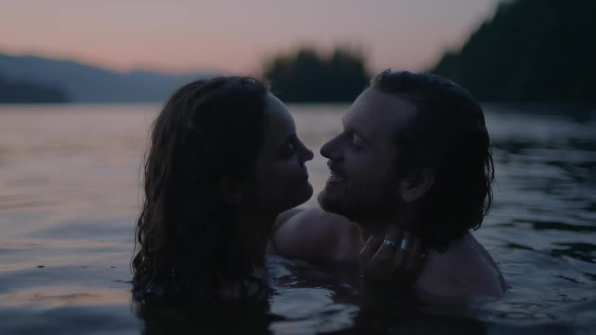 A white man and a woman hold each other while in water
