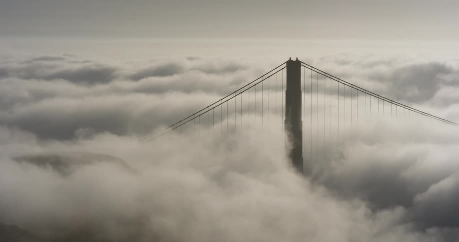 The supports of a bridge protruding from the mist