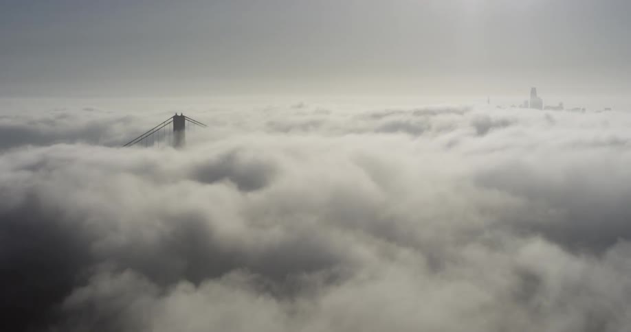 Aerial view of a cable bridge surrounded in white clouds