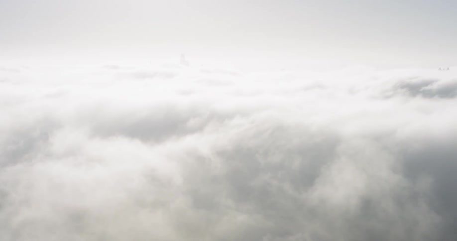 A suspension bridge is shrouded in thick white fog