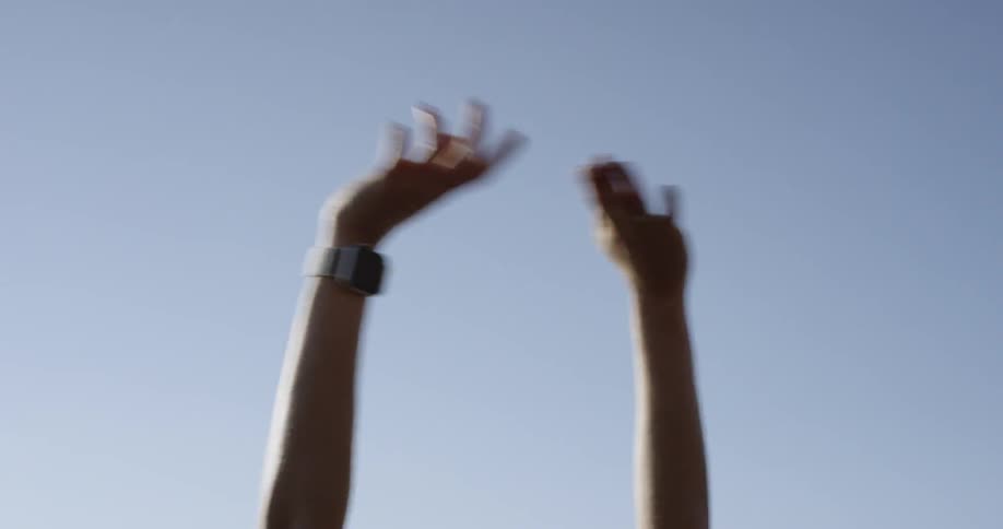 A woman holding her hands over her head with the sky in the background
