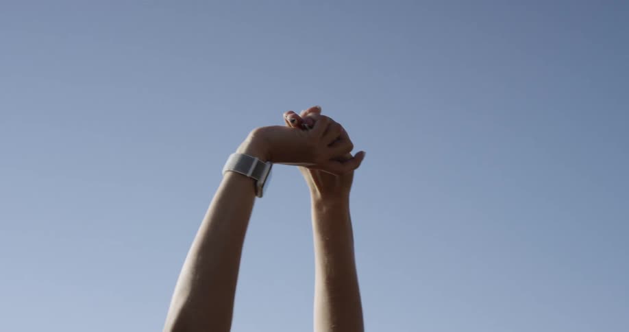 A person stretches their arms to the sky locking hands then lowers them
