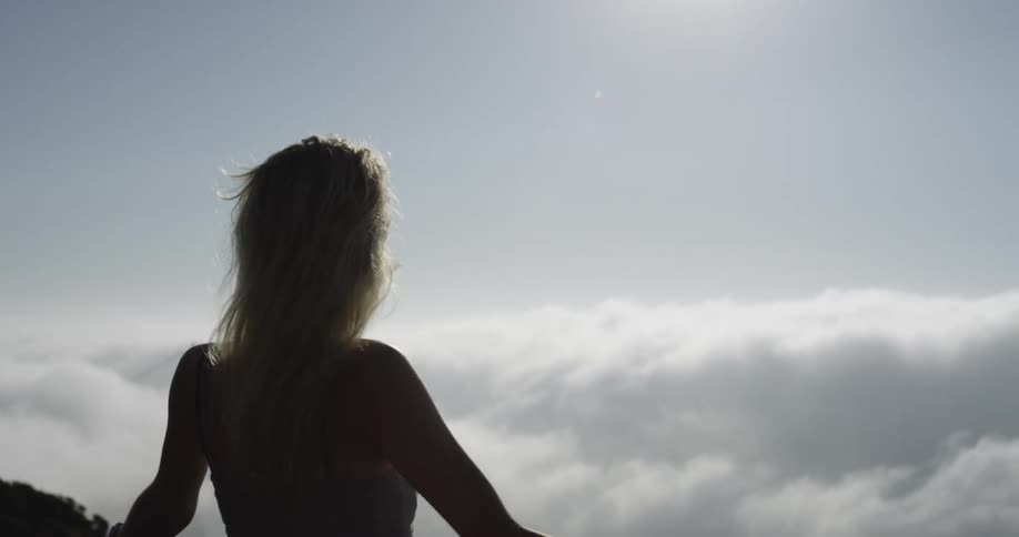 Blonde female walking over to edge looking out to clouds below
