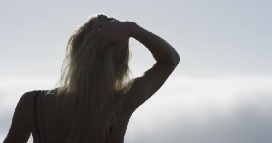 A woman brushes her hair back outside