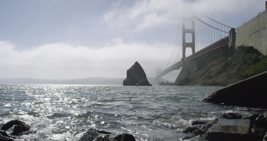 A rocky shore with a bridge and the sky in the background