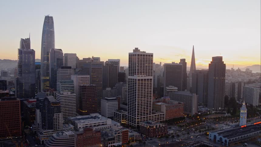 A harbor in front of a city skyline of skyscrapers at sunset
