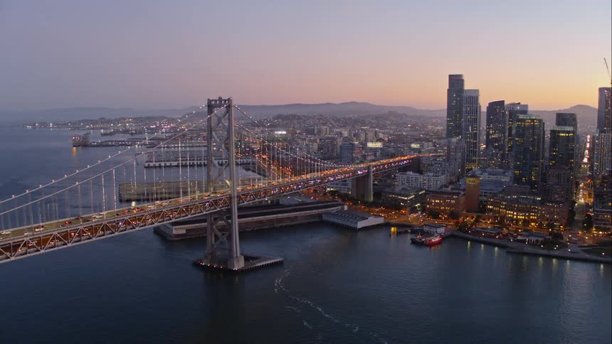 Aerial view of cars traveling over a bridge from a waterfront downtownat sunset