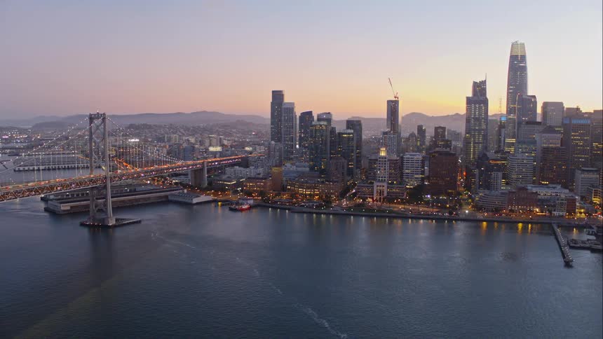 City skyline near harbor with suspension bridge at dawn