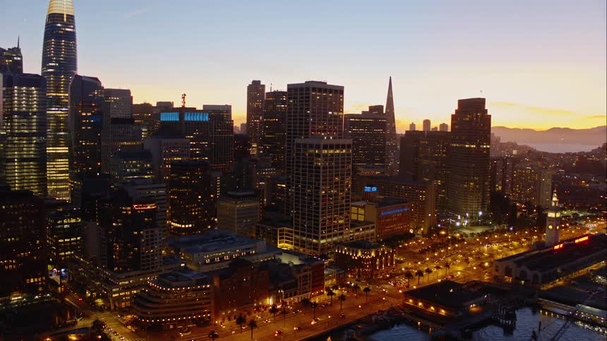 Ariel view of a metropolis city off the bay at sunset with many lights shining