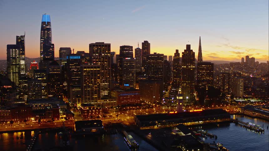 A marina in front of a busy urban location with skyscrapers at sunset