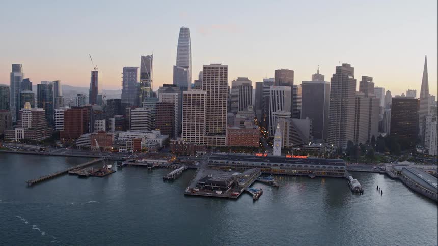 Downtown city bordering ocean with mountains on the horizon