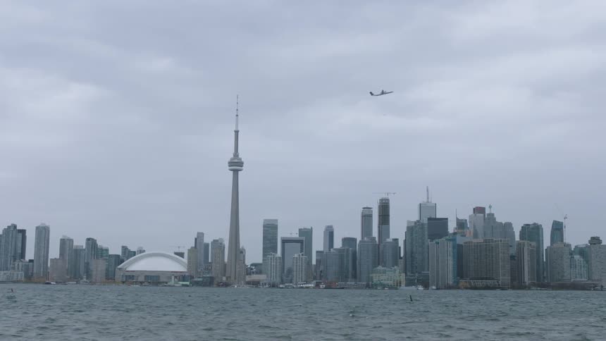 An airplane flies over a cloudy city skyline
