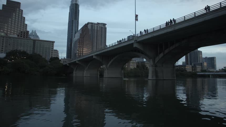 People standing on a city bridge look out over the water