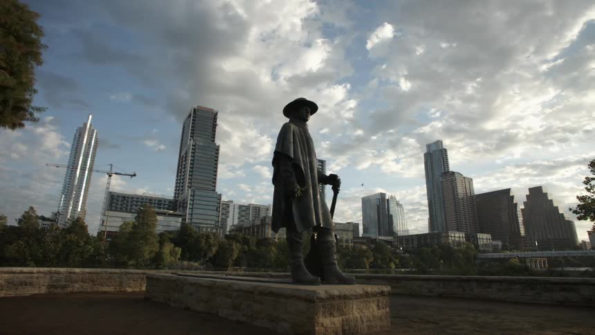 A statue in a public park with a skyline in the background
