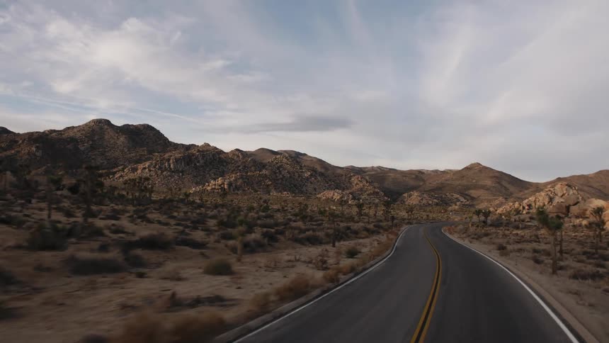 Driving along a winding desert road towards a mountain