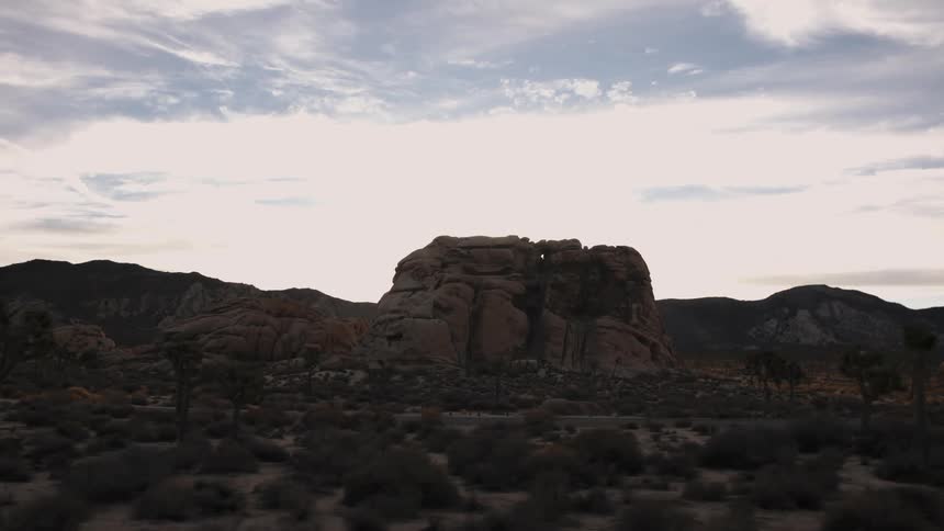 Mountains and large rocks in a desert with bushes and cacti