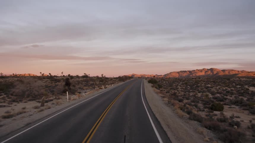 Driving down a desert road as the sun sets