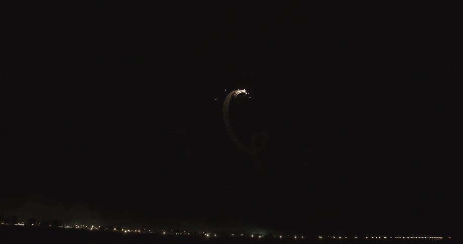A firework swirls and dips in a dark night sky