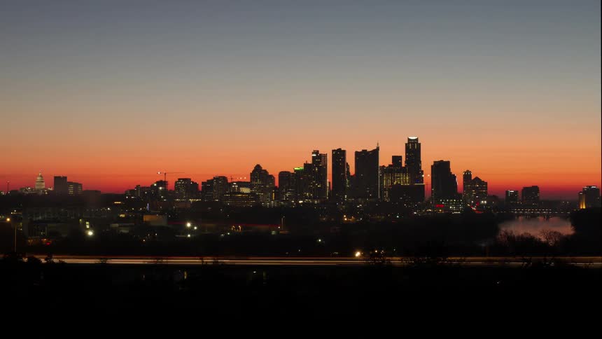 Timelapse of evening city traffic with a skyline in the background