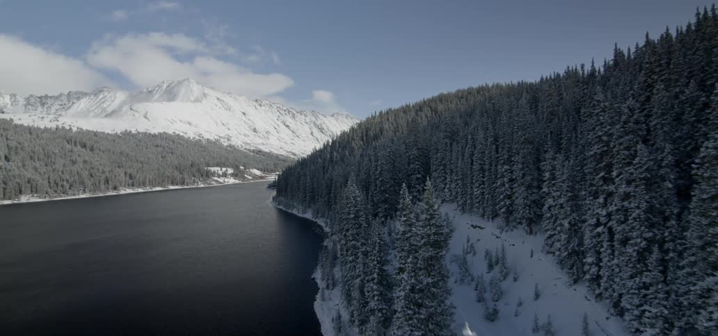 Snow is covering the mountainside and hills along the shore