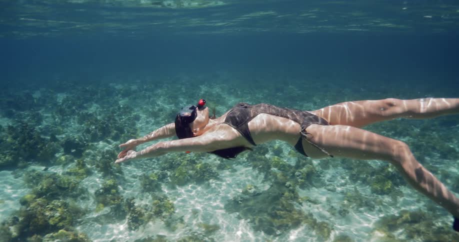 A woman swims in shallow open waters while wearing a snorkel and flippers