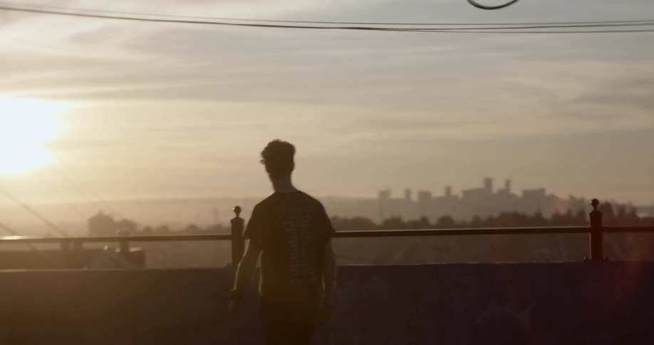 A man walks on a large balcony near a bridge that overlooks a city