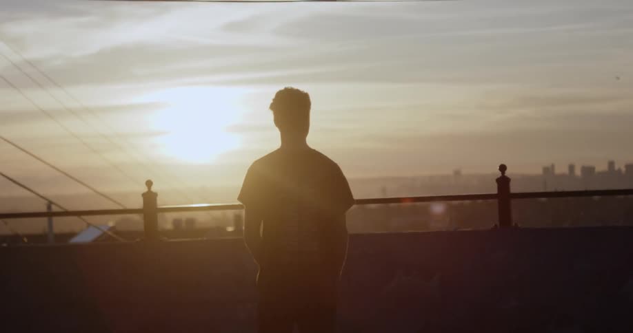 A man walks to the fence overlooking the city