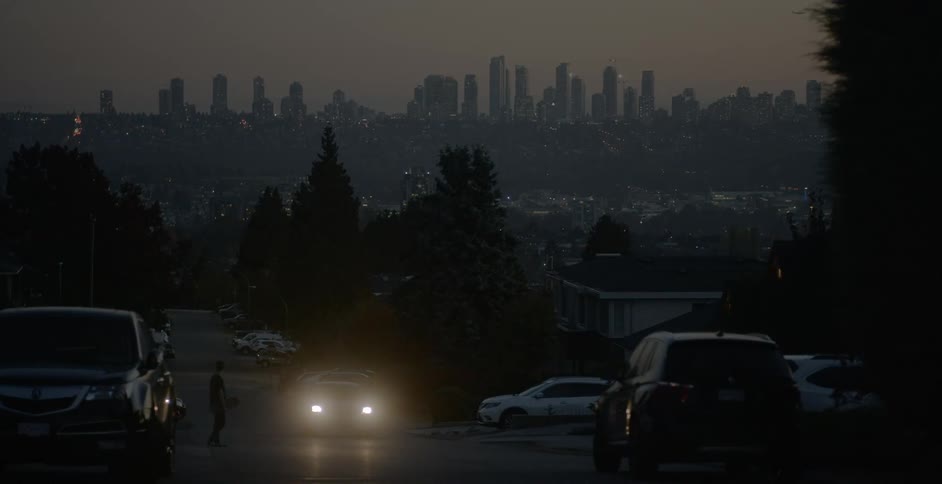A car drives past a pedestrian in a suburb of a big city