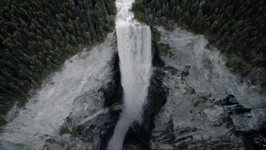 A river running through a forest and becoming a waterfall down a high cliff
