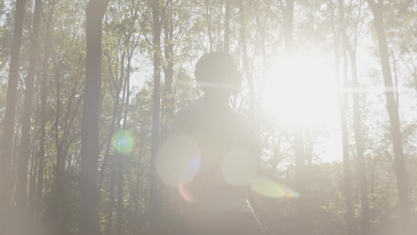 Sunlight shines on a man standing alone in a forest