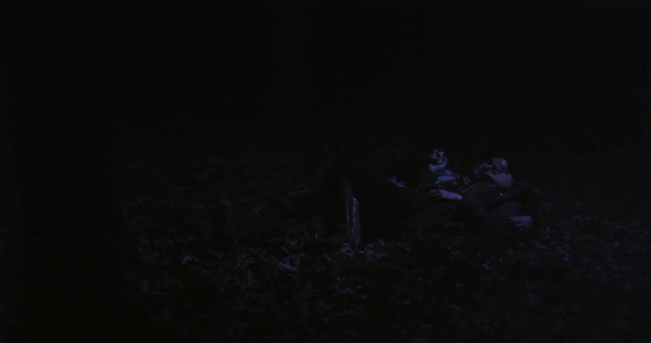 Man and woman lay on the ground snuggling at night