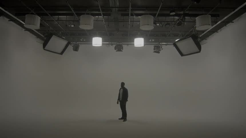 Man stands in white room under lights