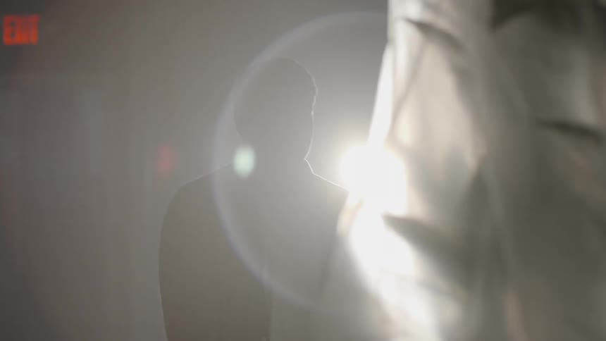 A man pushes a plant wrapped in a white cloth through a room