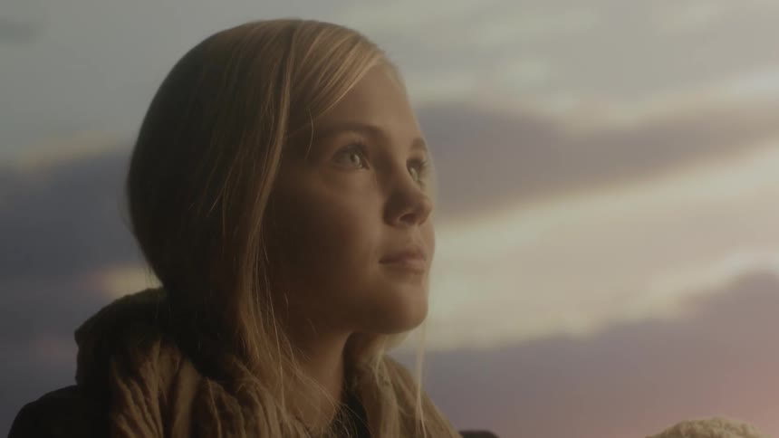 A blonde girl holds a baby while standing outside at sunset