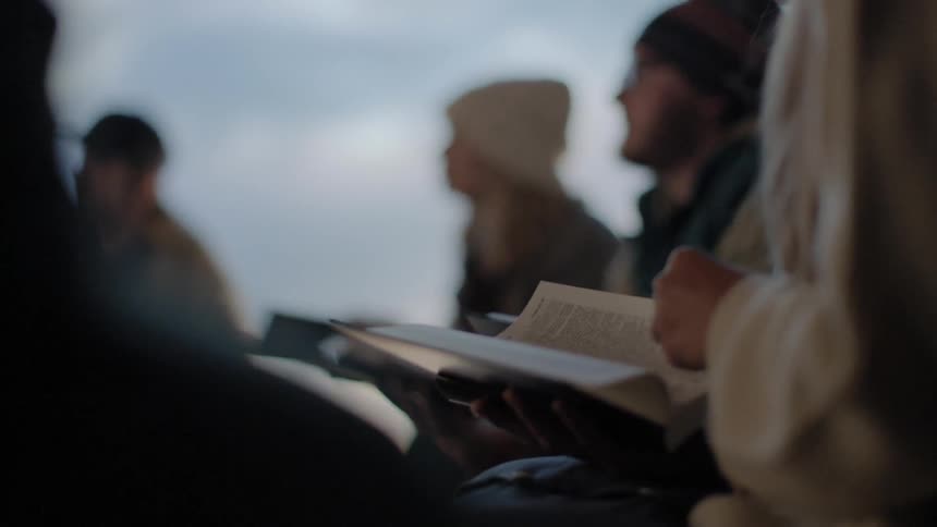 People in winter clothes sit outside with books in their hands