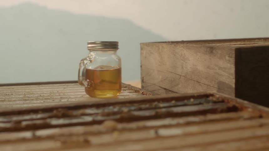 Close up of a jar of honey over a beehive