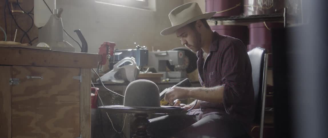 Man polishes a wool hat with a handheld tool