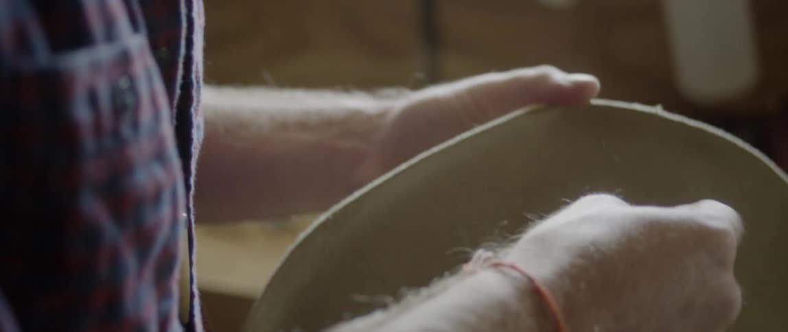 A man threads string through a hat