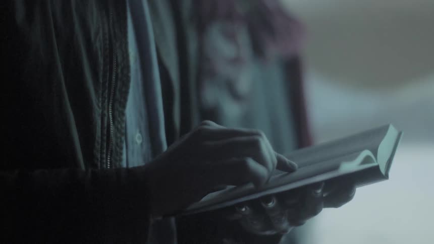 A young man looks down and reads a book