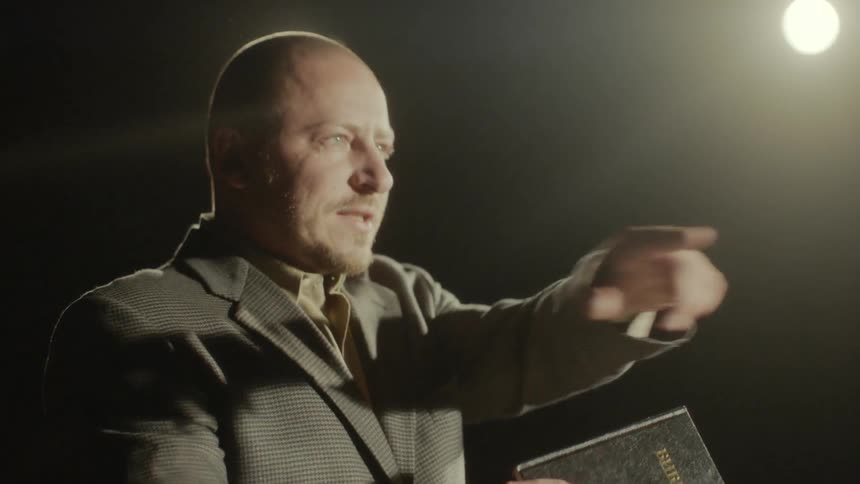 Man stands in the lights and shows a book to the audience