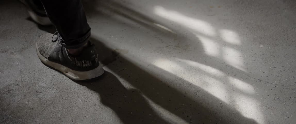 Man wearing jeans and sneakers walks on the concrete during daylight