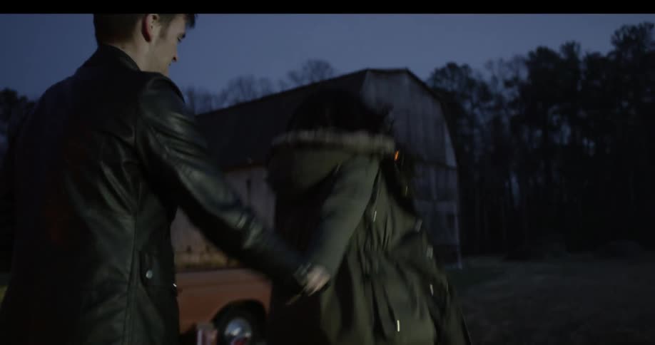 People are walking towards a barn at sunset