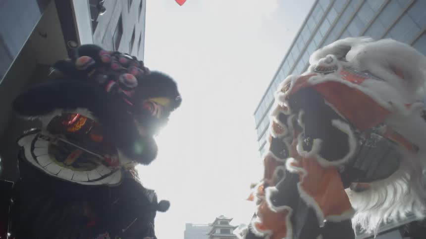 Two guys holding up and twirling large costume heads in the city