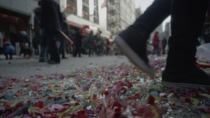 A person is walking in the street littered with confetti