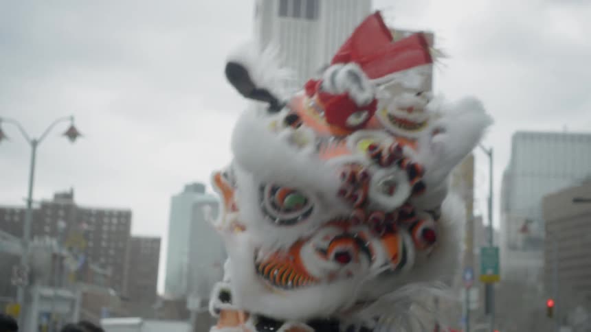People wearing a chinese dragon costume dance in an urban street