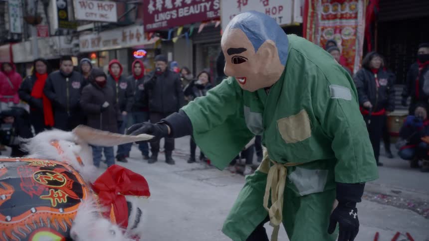 Dancers in costumes dance in a street for an audience