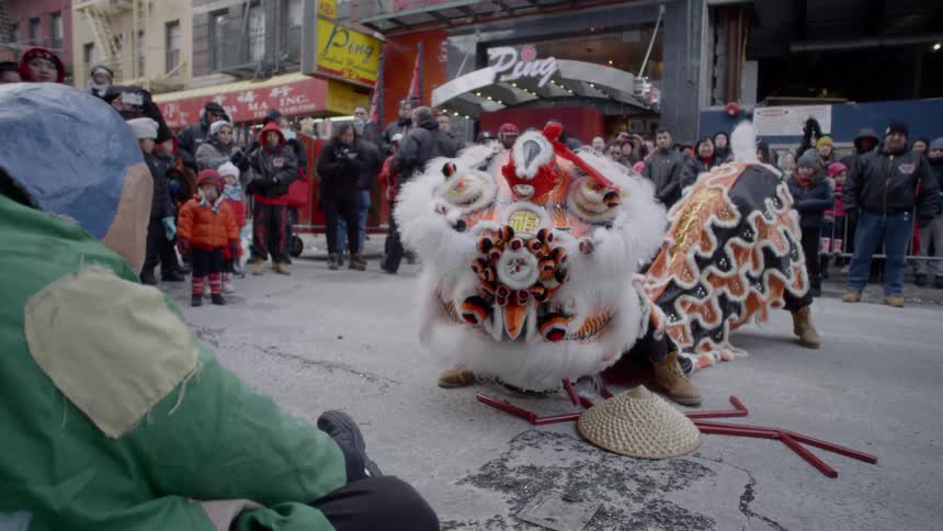 People in chinese festival costumes dance on a street while crowd watches